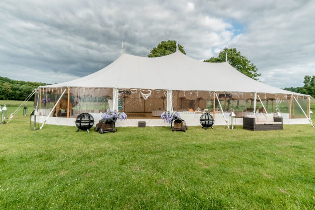 Big top cream marquee on green grass with a cloudy but blue sky