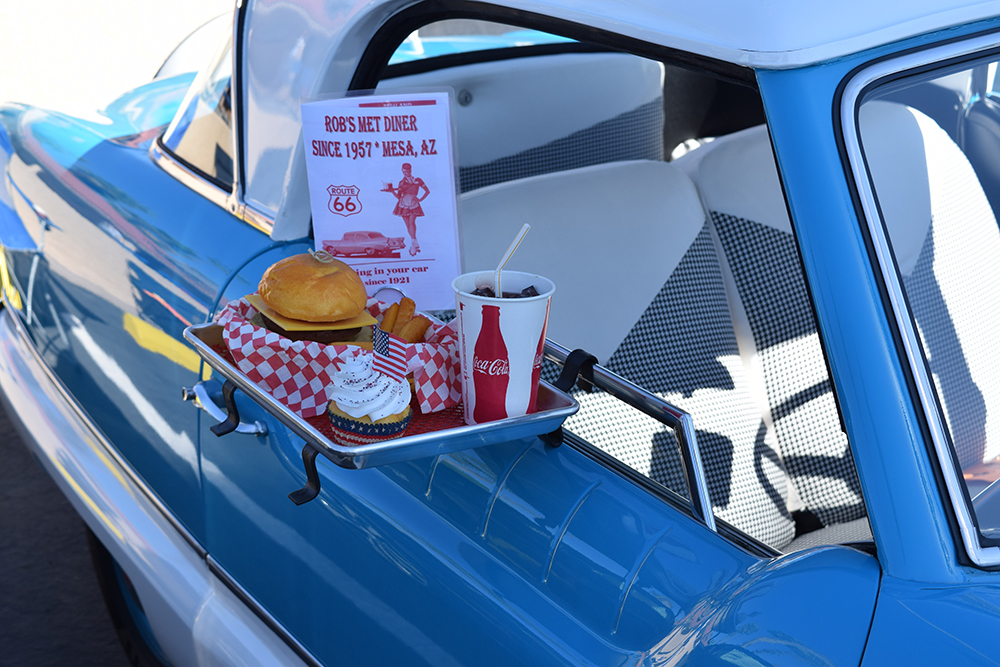 Drive-in hamburger meal clipped to the lowered side window of a blue car