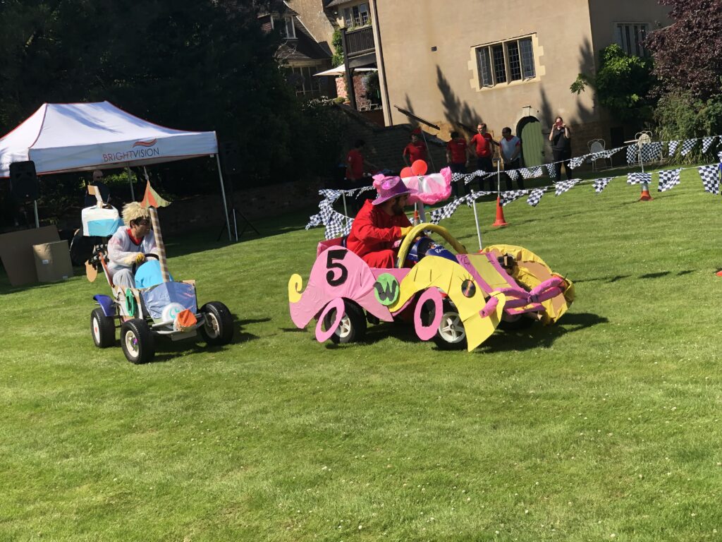 two people in two decorated go-karts racing on grass