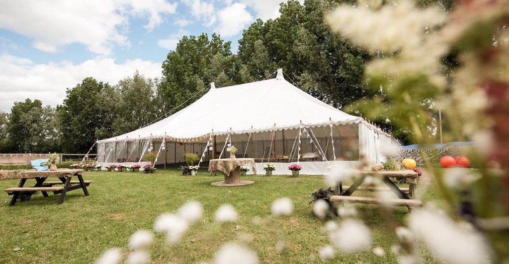 White big top type marquee in a field with trees behind